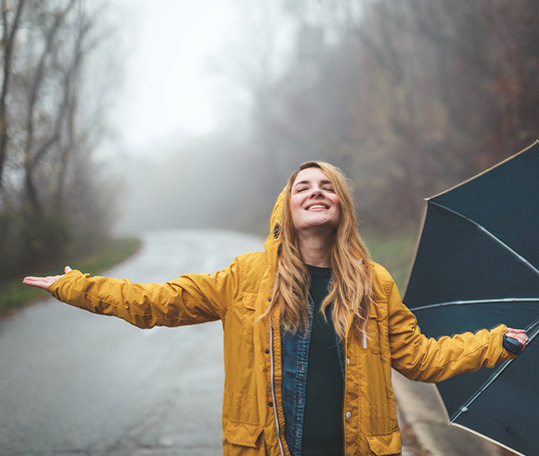 Joyful woman walking in rainy weather